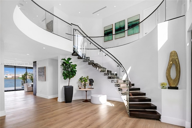 stairway with a towering ceiling and hardwood / wood-style flooring