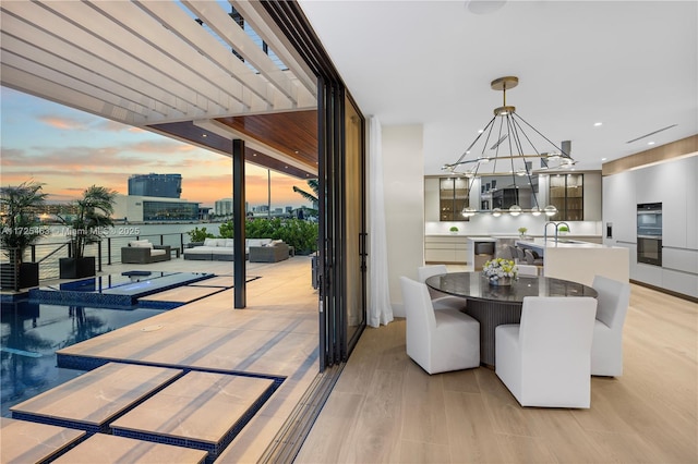 dining space featuring expansive windows, sink, a chandelier, and light hardwood / wood-style floors