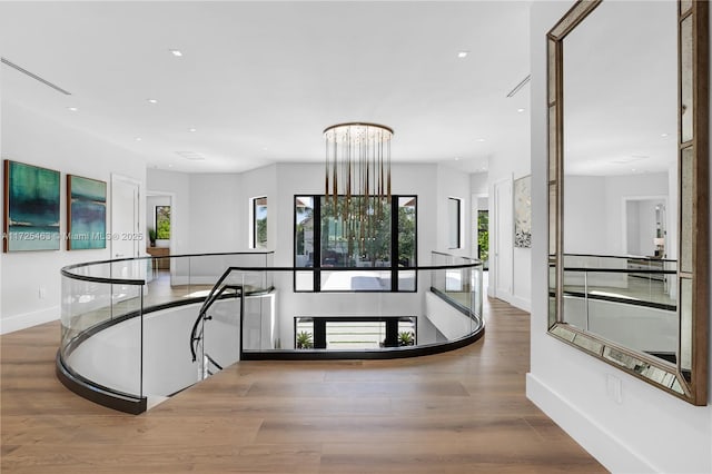 hallway with hardwood / wood-style floors and a notable chandelier