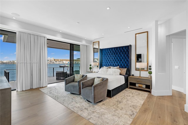 bedroom with a water view, access to exterior, and light wood-type flooring