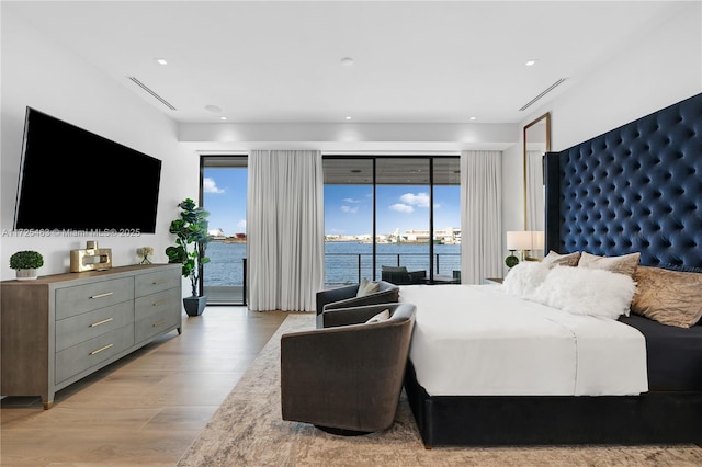 bedroom with a water view, access to outside, and light wood-type flooring