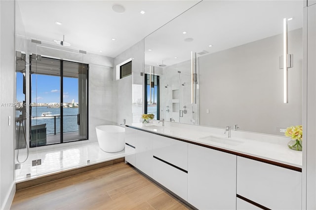 bathroom with vanity, wood-type flooring, plus walk in shower, and a water view