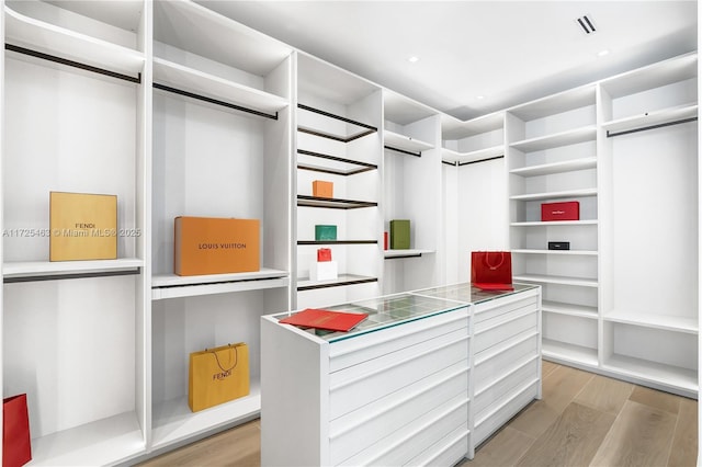 walk in closet with light hardwood / wood-style floors