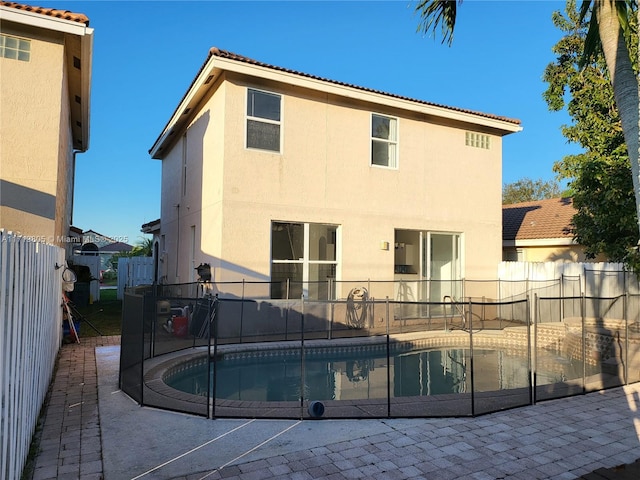 back of property featuring a patio area and a fenced in pool