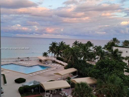 pool at dusk with a patio and a water view