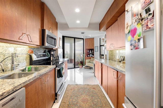 kitchen with sink, decorative backsplash, light stone counters, and appliances with stainless steel finishes