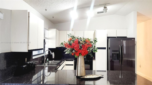 kitchen featuring stainless steel fridge with ice dispenser, a textured ceiling, white cabinets, lofted ceiling, and sink