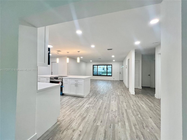 kitchen with stainless steel electric range oven, white cabinets, decorative light fixtures, light hardwood / wood-style flooring, and kitchen peninsula