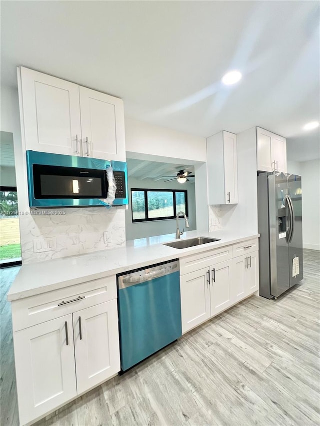 kitchen with sink, white cabinetry, light hardwood / wood-style floors, decorative backsplash, and stainless steel appliances