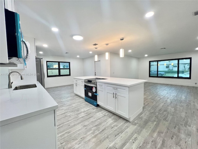 kitchen featuring appliances with stainless steel finishes, sink, decorative light fixtures, white cabinets, and a center island