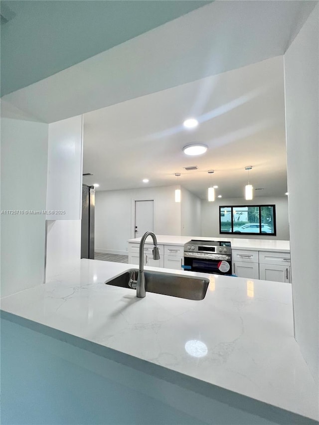 kitchen featuring white cabinetry, sink, decorative light fixtures, electric range, and kitchen peninsula