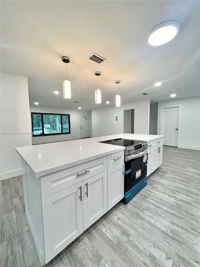 kitchen featuring white cabinetry, light hardwood / wood-style flooring, pendant lighting, and stainless steel range with electric cooktop