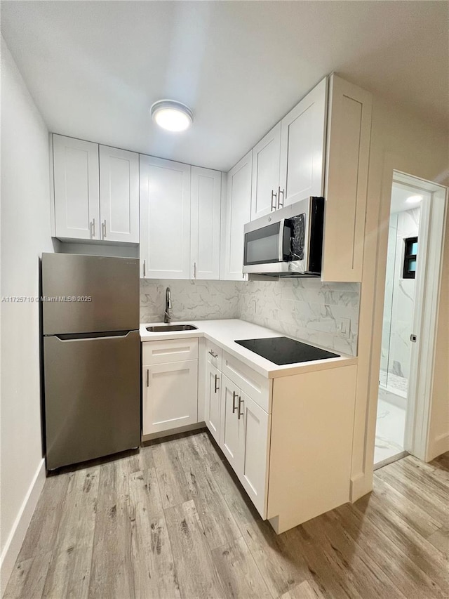 kitchen with sink, light hardwood / wood-style floors, white cabinetry, and stainless steel appliances