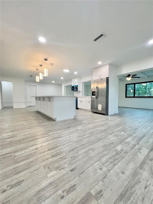 unfurnished living room featuring ceiling fan, sink, and light hardwood / wood-style flooring