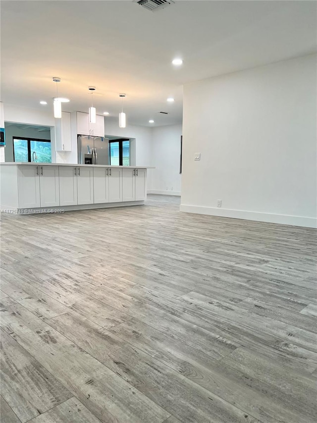 unfurnished living room featuring sink and light hardwood / wood-style flooring