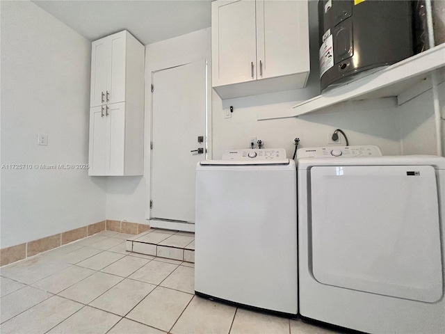 clothes washing area with baseboard heating, cabinets, light tile patterned floors, and washing machine and clothes dryer