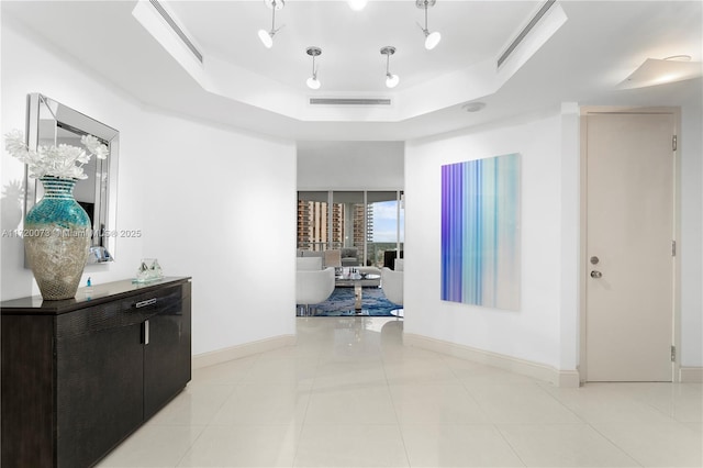 hallway featuring a raised ceiling and light tile patterned floors