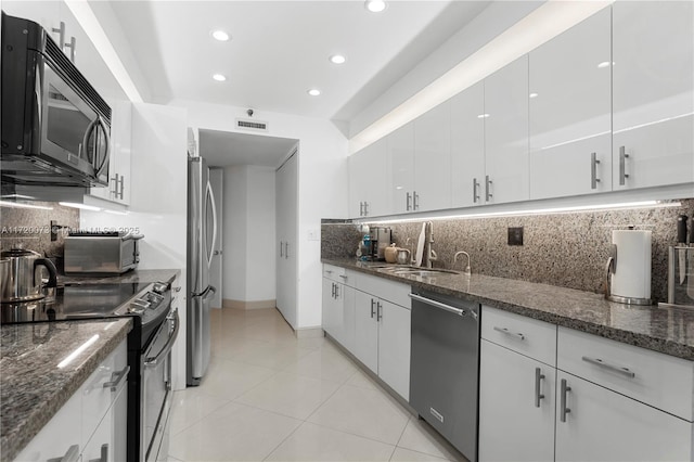 kitchen featuring sink, white cabinetry, dark stone countertops, and appliances with stainless steel finishes