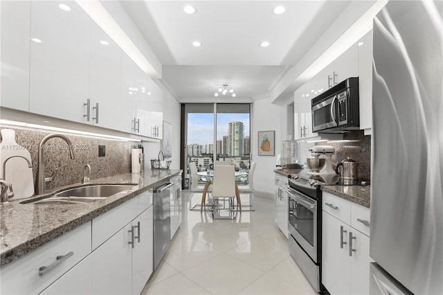 kitchen featuring stainless steel appliances, white cabinets, tasteful backsplash, and dark stone counters