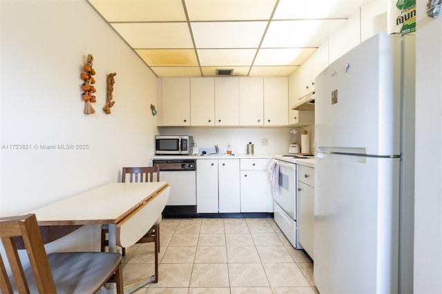 kitchen featuring white appliances, light tile patterned floors, a drop ceiling, white cabinets, and sink