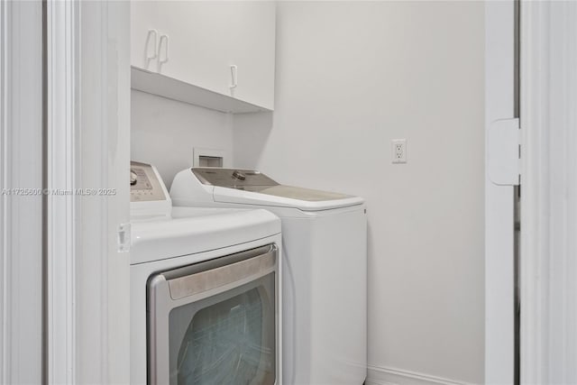 clothes washing area featuring washer and clothes dryer and cabinets