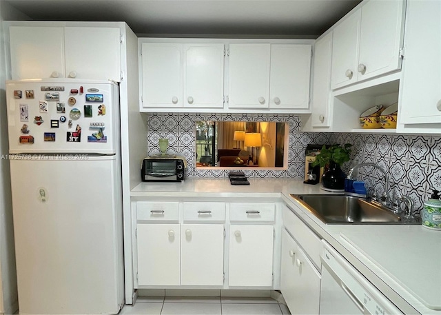 kitchen with white appliances, light tile patterned floors, decorative backsplash, white cabinets, and sink