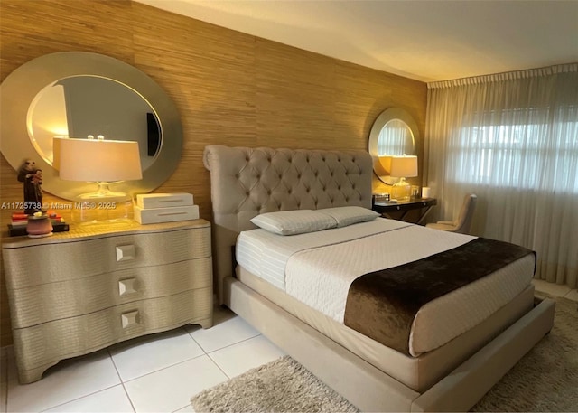 bedroom with wooden walls and light tile patterned floors