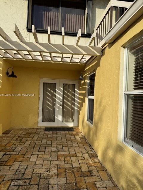 view of exterior entry with a balcony and a patio