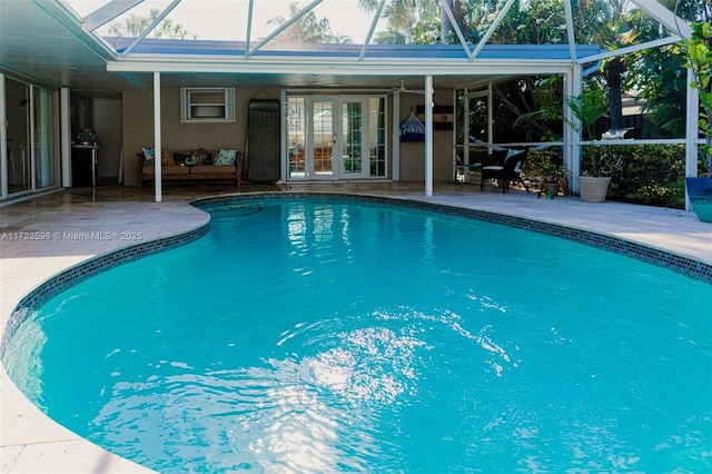 view of swimming pool featuring glass enclosure, a patio, and french doors