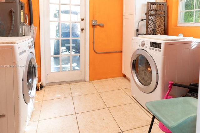 laundry room featuring washer and clothes dryer, light tile patterned floors, and cabinets