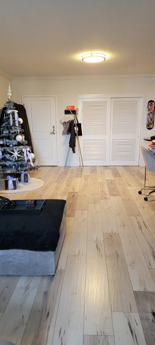 interior space with a textured ceiling, crown molding, and hardwood / wood-style flooring