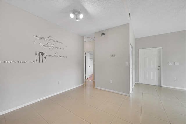 spare room featuring a textured ceiling and light tile patterned flooring