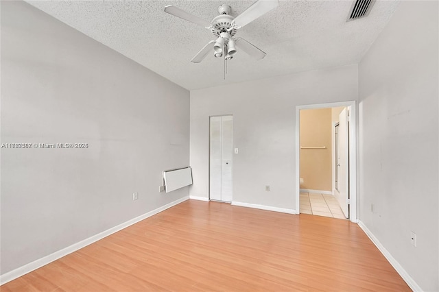 unfurnished room featuring a textured ceiling, ceiling fan, and light hardwood / wood-style flooring