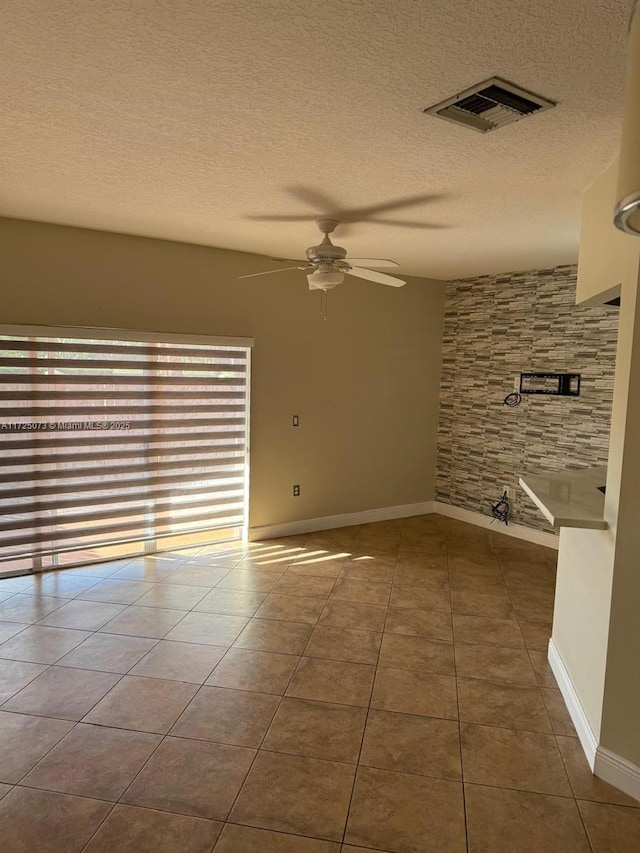 empty room with ceiling fan, dark tile patterned flooring, and a textured ceiling