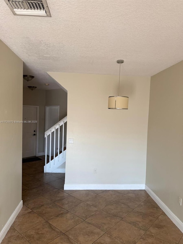 tiled spare room featuring a textured ceiling