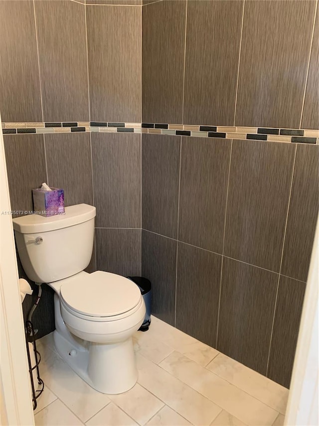 bathroom featuring tile patterned flooring, tile walls, and toilet