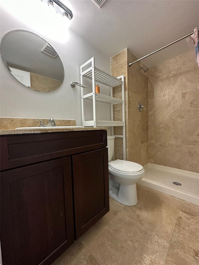 bathroom featuring toilet, a tile shower, and vanity