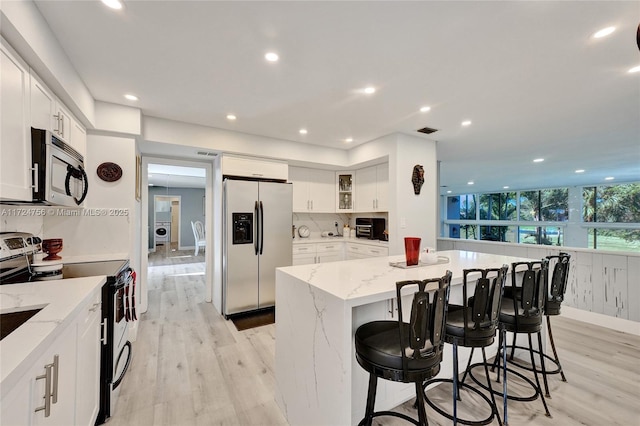 kitchen featuring stainless steel appliances, a kitchen bar, a center island, and white cabinets