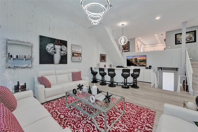 living room with a notable chandelier, hardwood / wood-style flooring, and wood walls