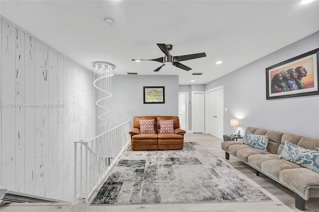 living room with light hardwood / wood-style flooring, wooden walls, and ceiling fan