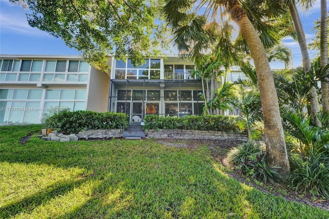 rear view of property with a balcony and a lawn