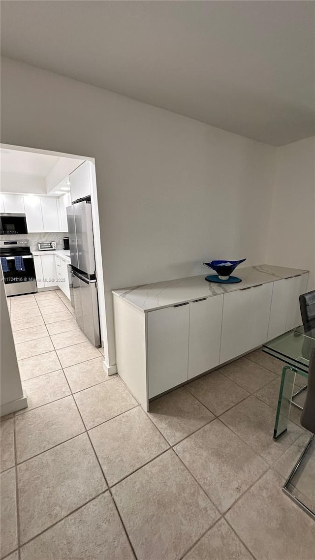 kitchen featuring white cabinets, stainless steel appliances, decorative backsplash, and light tile patterned floors