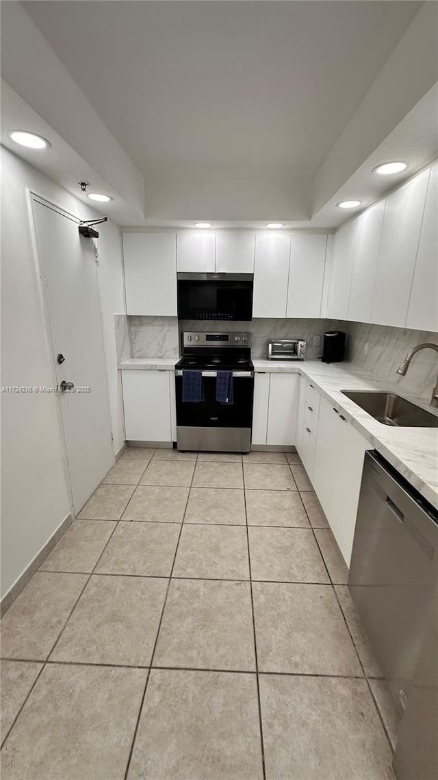 kitchen with sink, white cabinetry, tasteful backsplash, light tile patterned floors, and appliances with stainless steel finishes