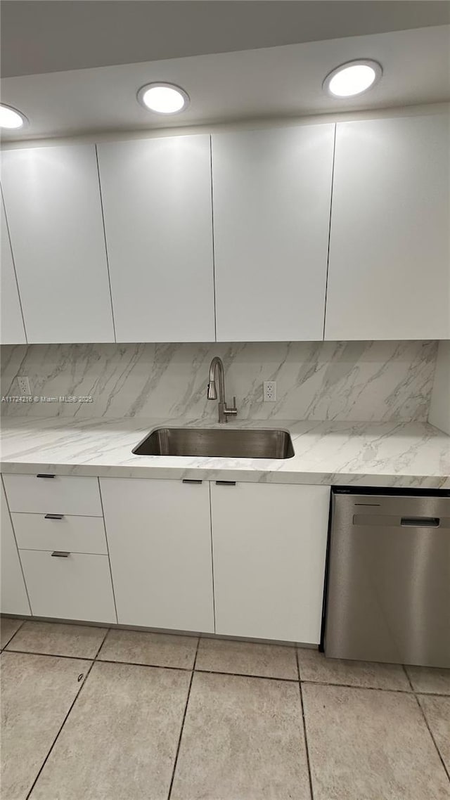 kitchen featuring sink, white cabinetry, stainless steel dishwasher, and light stone counters