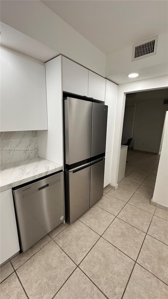 kitchen with stainless steel appliances, white cabinetry, tasteful backsplash, and light stone counters