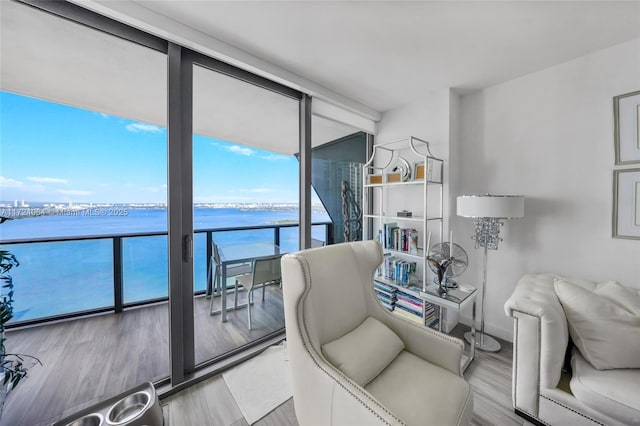 living room with light hardwood / wood-style flooring, expansive windows, and a water view