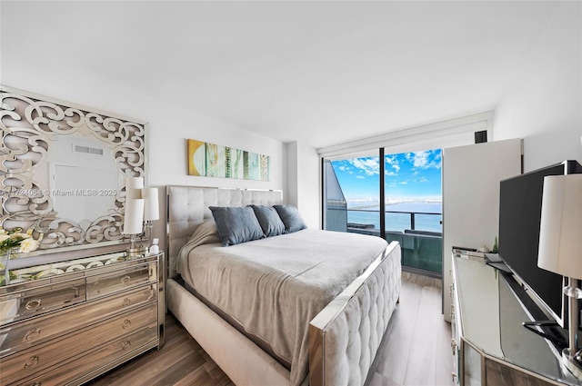 bedroom featuring dark wood-type flooring, a wall of windows, and access to exterior