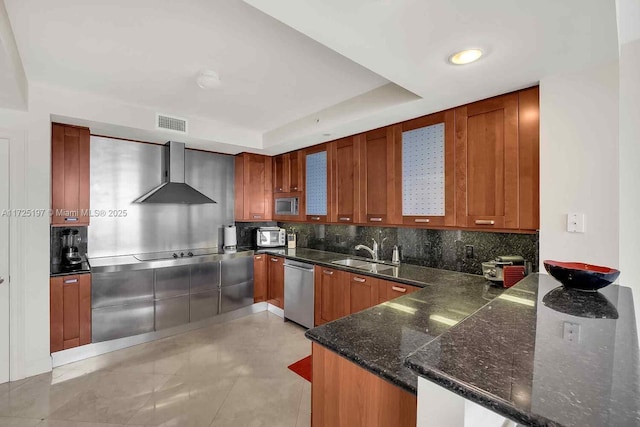 kitchen featuring wall chimney range hood, sink, dishwasher, tasteful backsplash, and kitchen peninsula