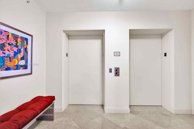 hallway with elevator and light tile patterned floors