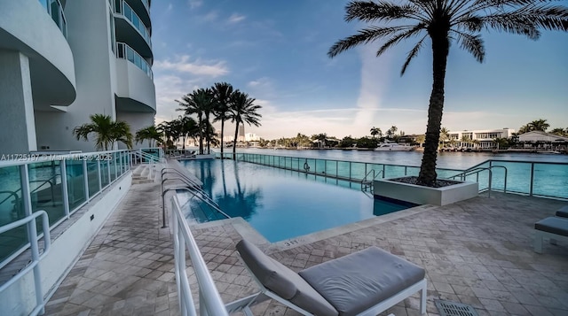 pool at dusk featuring a water view